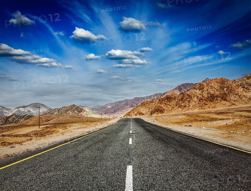 Travel forward concept background, road in Himalayas with mountains and dramatic clouds. Ladakh, Jammu and Kashmir, India, Asia