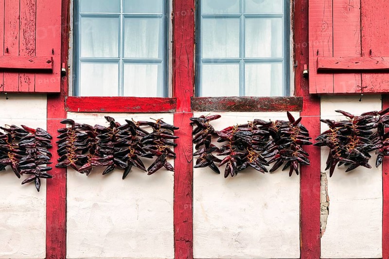 Chilli peppers, Piment dEspelette hanging to dry on facade, typical window with red shutters, detail, Espelette, Département Pyrénées-Atlantiques. Region Nouvelle-Aquitaine, Pays Basque, Basque Country, France, Europe