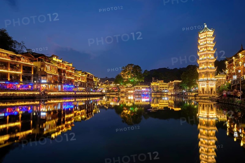 Chinese tourist attraction destination, Feng Huang Ancient Town (Phoenix Ancient Town) on Tuo Jiang River with Wanming Pagoda illuminated at night. Hunan Province, China, Asia