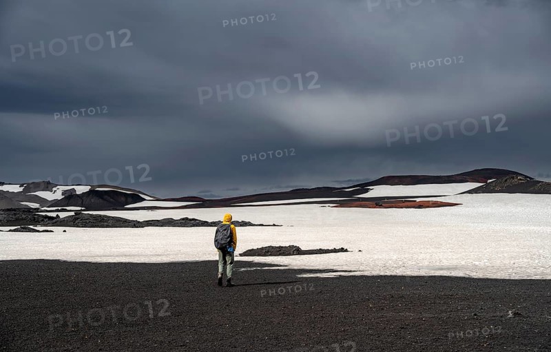 Hikers in snow-covered volcanic landscape with volcanic sand and petrified lava, crater of Askja volcano, Icelandic highlands, Iceland, Europe