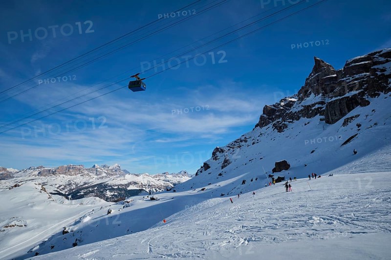 View of a ski resort piste with people skiing in Dolomites in Italy with cable car ski lift. Ski area Arabba. Arabba, Italy, Europe
