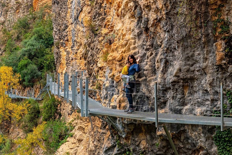 Very happy woman and son walking along the metal walkways of the Vero River path in Alquezar. Pyrenees