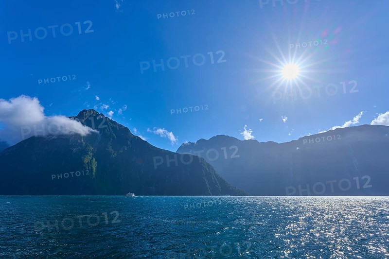 Bright sun over mountains and an expanse of water, summer, Milford Sound, Te Anau, Fiordland National Park, South Island, New Zealand, Oceania