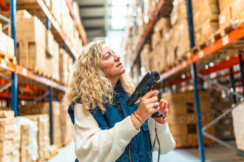 Woman worker looking up while scanning the barcode of packages in a warehouse