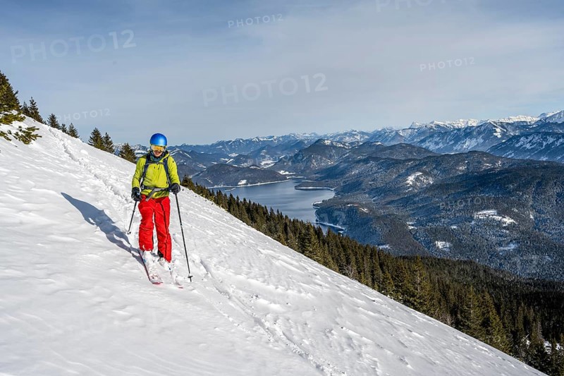 Skiers skiing down the Simetsberg, view of Walchensee and mountain panorama, Estergebirge, Bavarian Prealps, Bavaria Germany
