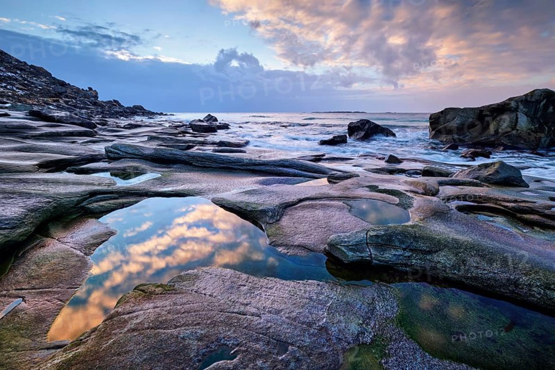 Rocks on beach of fjord of Norwegian sea in winteron sunset. Utakliev beach, Lofoten islands, Norway, Europe