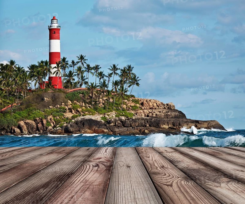 Wood planks floor with old lighthouse and sea waves in background