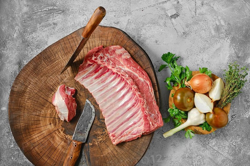 Overhead view of raw fresh lamb ribs on wooden slab