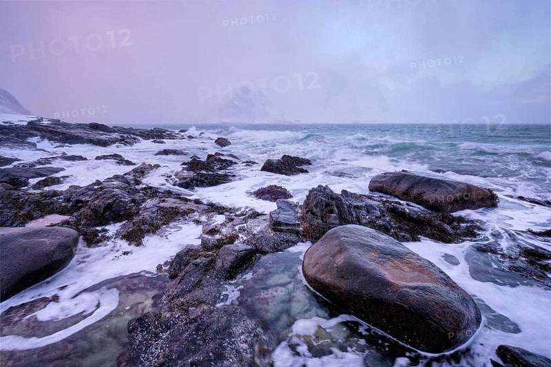 Beach of Norwegian sea on rocky coast in fjord on sunset in winter. Vareid beach, Lofoten islands, Norway, Europe