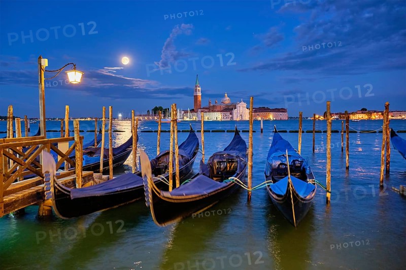 Romantic vacation Venice travel background, gondolas at Saint Mark (San Marco) square and Basilica San Giorgio Maggiore Church seen across Venice lagoon with full moon. Venice, Italy, Europe