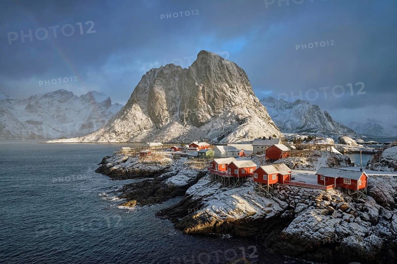 Hamnoy fishing village on Lofoten Islands, Norway with red rorbu houses. With falling snow in winter and rainbow