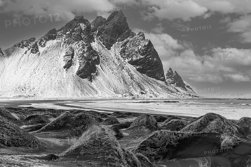 Black sand dunes with reed remains, behind them snowy rocky slopes of Vestrahorn, black and white photo, near Höfn, Sudausturland, Iceland, Europe
