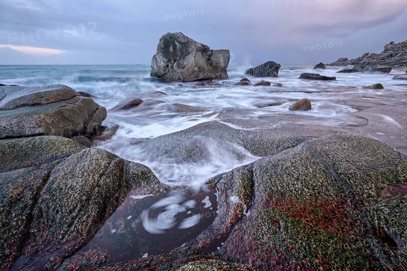 Rocks on beach of fjord of Norwegian sea in winteron sunset. Utakliev beach, Lofoten islands, Norway, Europe