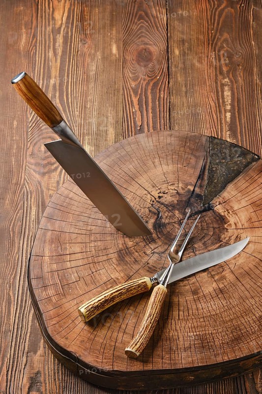 Overhead view of cleaver, fork and knife on wooden stump