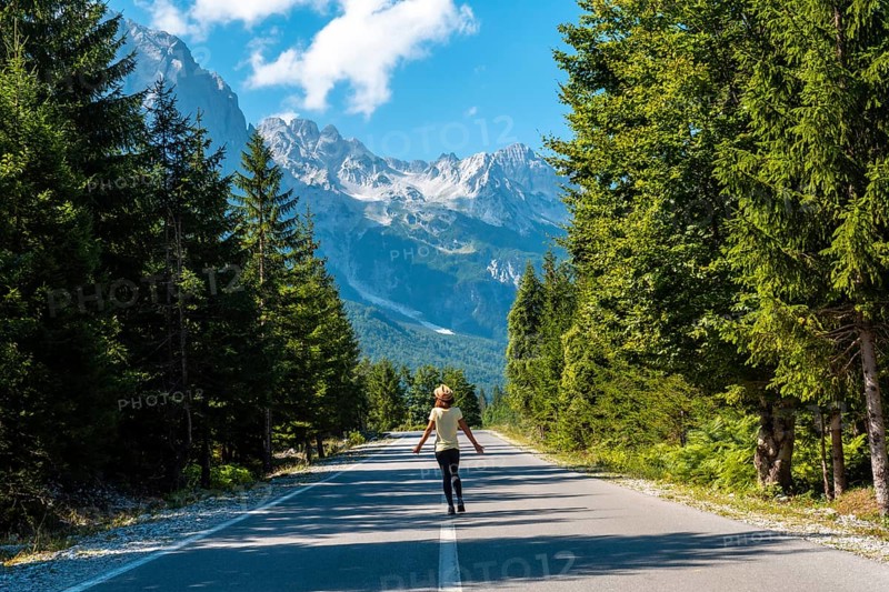 A young tourist woman walking on the road in the Valbona valley, Theth national park, Albanian Alps, Valbona Albania