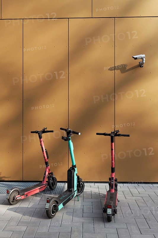 Three e-scooters correctly parked on the pavement, under a surveillance camera, Düsseldorf, North Rhine-Westphalia, Germany, Europe