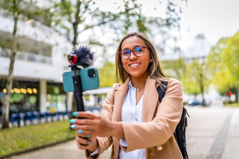 Stylish female latin vlogger smiling while recording new content in the city