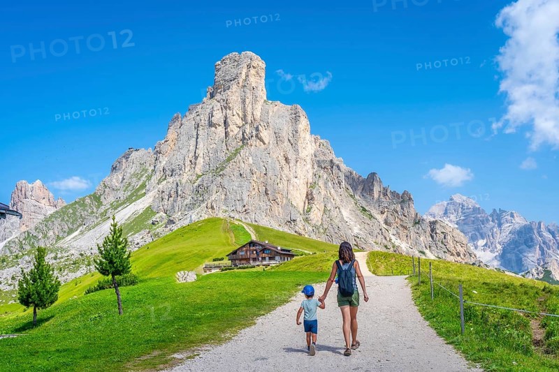 Mother and son walking on a path near the impressive giau pass in the italian dolomites, enjoying summer vacation