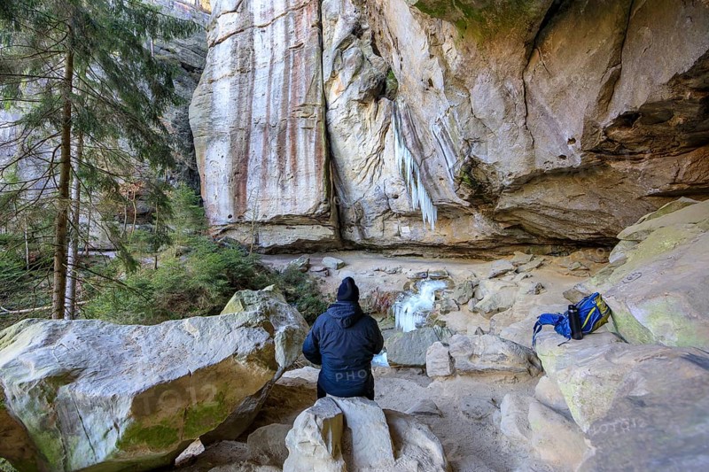 Hiker taking a break, frozen waterfall with icicles in the Gautschgrotte, Hohnstein, Saxony, Germany, Europe