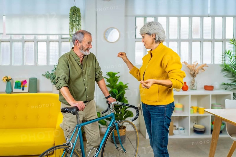 Senior couple talking while holding bike in the apartment. Sustainable way of life