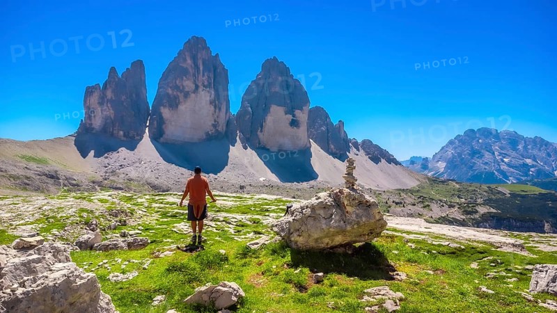 Tourist enjoying the breathtaking view of the tre cime di lavaredo peaks while hiking in the italian dolomites on a sunny summer day