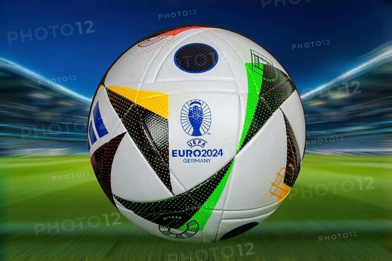 Symbolic image UEFA-EURO 2024: Close-up of the official match ball of the 2024 European Football Championship in Germany against the backdrop of a football arena (Composing)