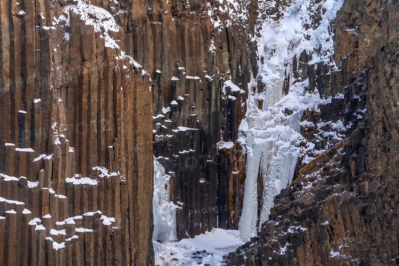 Hengifoss waterfall frozen in the cold winter of Iceland, volcanic cliffs