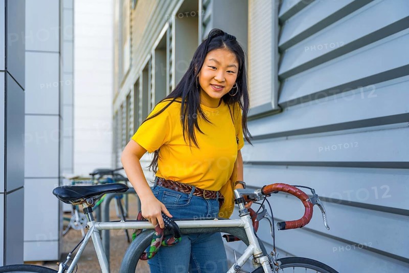 Portrait of a young chinese cute woman parking a bike in the street