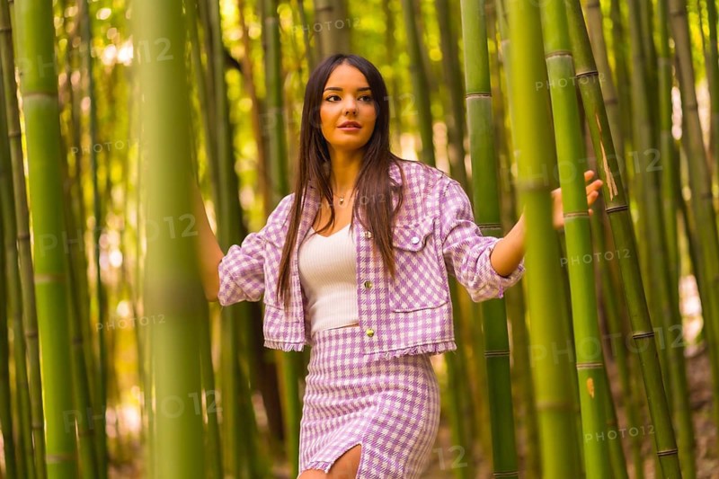 Young caucasian girl with a pink skirt in a bamboo forest. Enjoying the city on summer vacation in a tropical climate, lifestyle of a girl walking through the beautiful forest