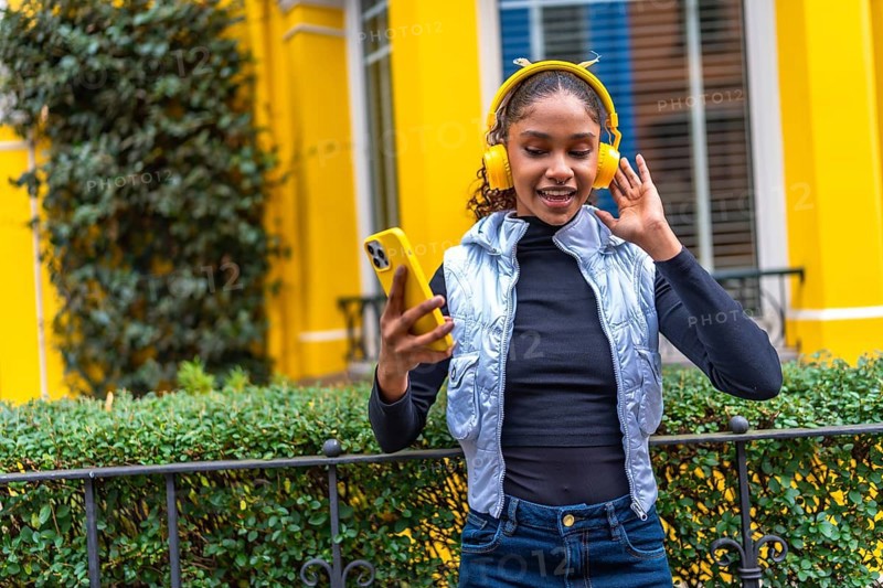 Frontal portrait of a cool urban african american urban woman dancing listening to music in the city