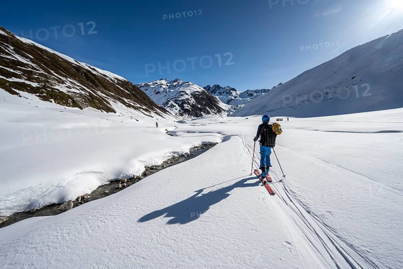 Ski tourer in the snow by a mountain stream in the Funtauna Valley, Graubünden Haute Route, Albula Alps, Rhaetian Alps, Graubünden, Switzerland, Europe