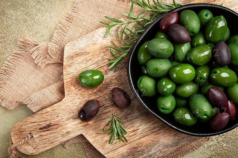 Chalkidiki olives, classic Greek green olives, in a bowl on a cutting board, top view, without people