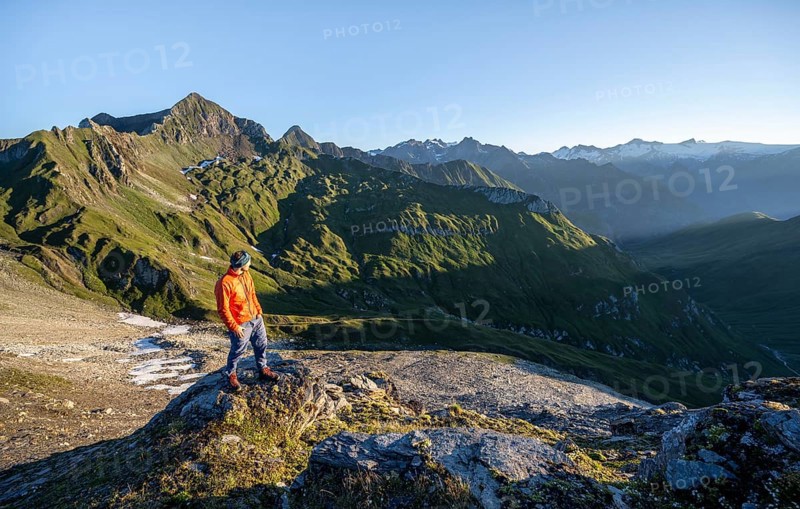 Mountaineer in front of mountain landscape at sunrise, view of mountain peaks of the Venediger group and into the Großbachtal valley from the summit of Bachlenkenkopf, Lasörling group, Hohe Tauern National Park, East Tyrol, Tyrol, Austria, Europe