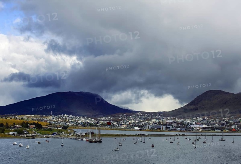 View of Ushuaia with sailing boats in front of cloudy mountains and cloudy sky, Ushuaia, Argentina, South America