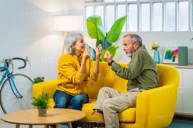 Full length photo of a caucasian senior couple arguing and discussing sitting on the sofa