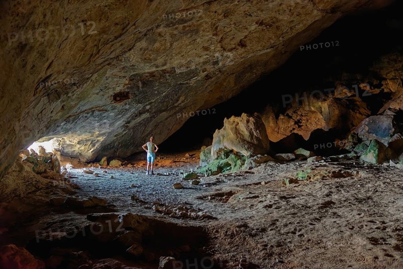 Woman in the darkness of the vast Limniatis Cave, Hike from Aperi to Limniatis Cave, Limniatis Cave, Aperi, Karpathos, Greece, Europe