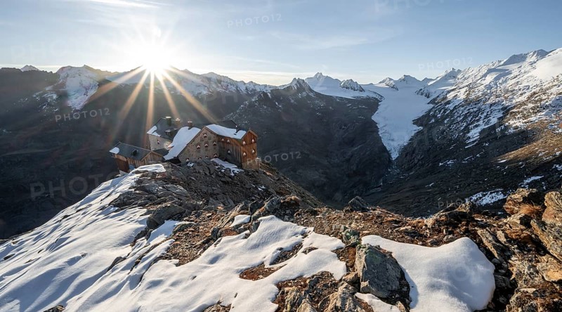 Mountain panorama and glacier, mountain hut Ramolhaus in autumn with snow, view of Gurgler Ferner with summit Hochwilde and Falschungsspitze, at sunrise with sun star, Ötztal Alps, Tyrol, Austria, Europe