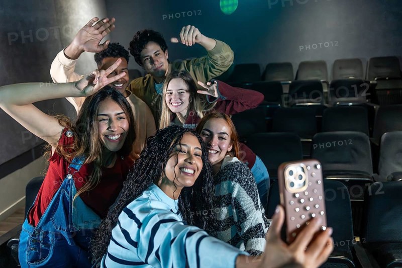 Group of smiling friends taking a selfie at the cinema, enjoying a movie night out together