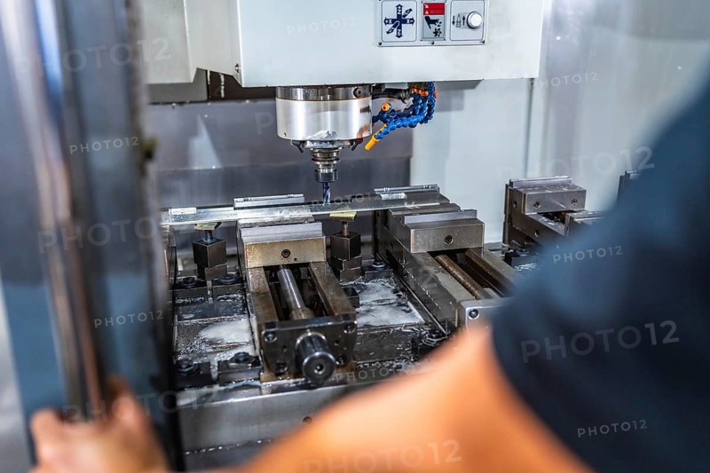 Rear view close-up of an unrecognizable man working with milling machine in cnc factory