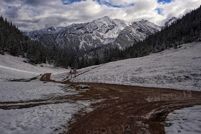 Picturesque view of snow-covered mountains on a path in front of dramatic clouds, Krün, Bavaria, Germany, Europe