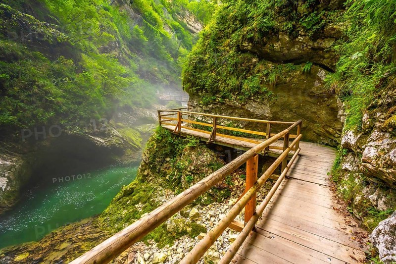 Breathtaking view of wooden walkway over stunning emerald river flowing through vintgar gorge near bled, slovenia, a picturesque natural wonder