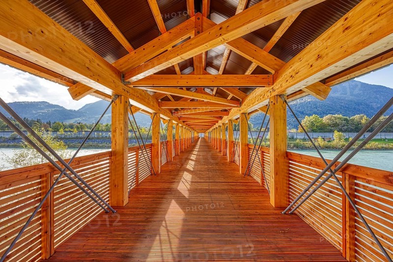 Perspective of a wooden bridge, framed by mountains and river, with modern construction, Inn footbridge, bridge over the Inn