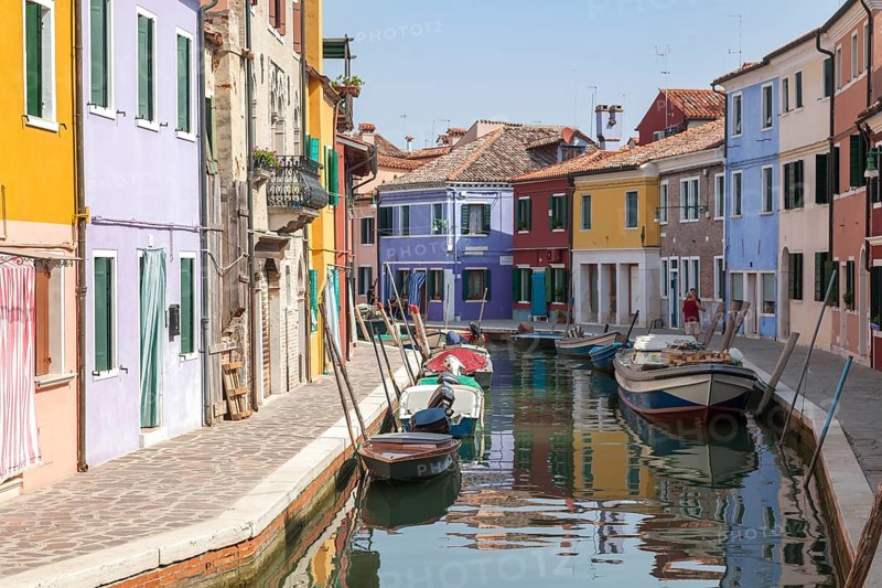 Colourful houses along a quiet canal with parked boats on the island of Burano, Venice, Italy, Europe