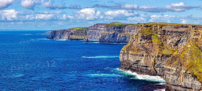 Sweeping views of steep cliffs and azure sea under a cloudy sky, Cliffs of Moher