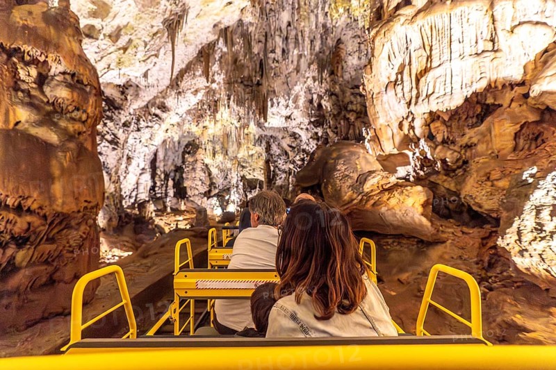 Tourists enjoying a train ride inside the magnificent postojna cave, a famous natural wonder in slovenia, during their family vacation