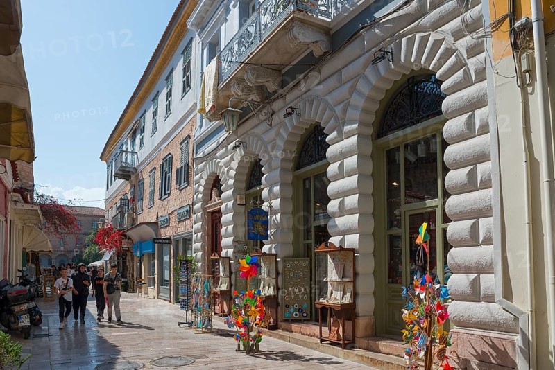 Lively shopping street with historic buildings, shop windows and colourful windmills under a blue sky, Nafplio, Nauplia, Nauplion, Nafplion, Argolis, Peloponnese, Greece, Europe