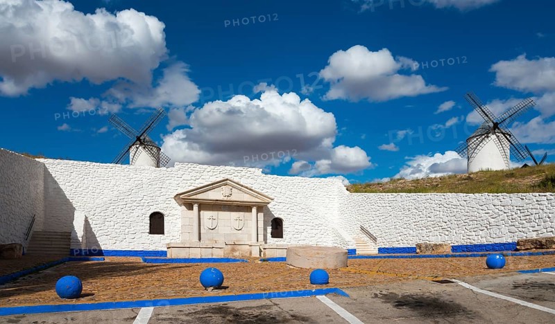 Two windmills and a stone wall against a blue sky full of clouds, Fuente del Caño, open-air museum, Campo de Criptana, Ciudad Real province, Castilla-La Mancha, Don Quixote Route, Spain, Europe