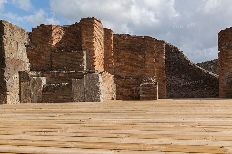 Wood plank decking and remnants of an old terracotta brick and stone wall structure at the ancient ruins of Pompeii, Campania region, Italy, Europe