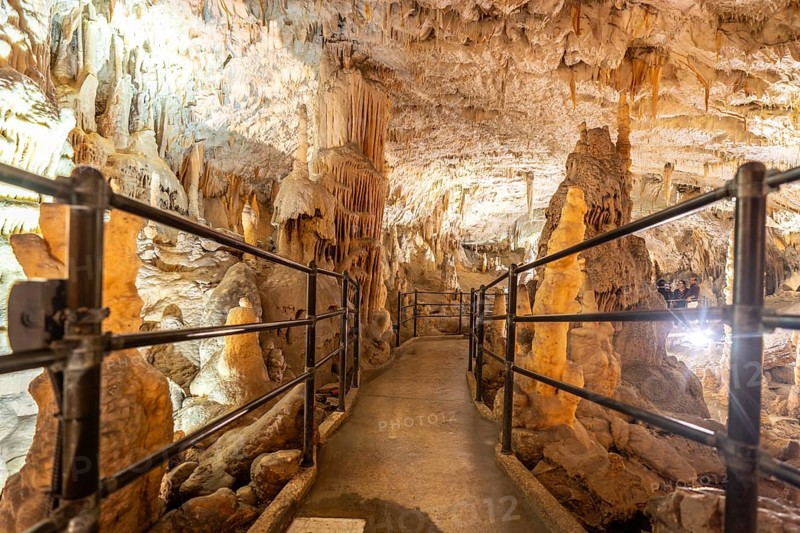 Tourists enjoy a train ride through the illuminated walkways of postojna cave, marveling at the breathtaking stalactite and stalagmite formations