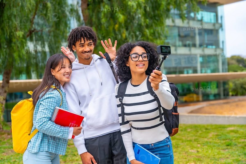 Three multi-ethnic students waving while recording a video with a wearable camera standing outside the campus